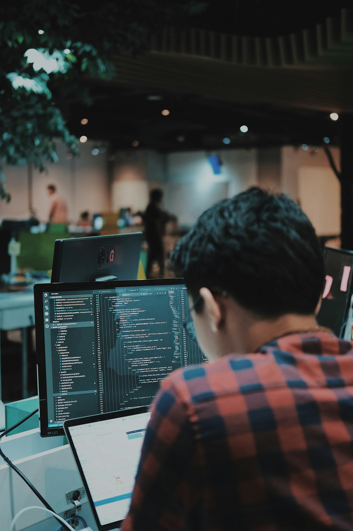 コードを表示したモニターに向かう人の後ろ姿